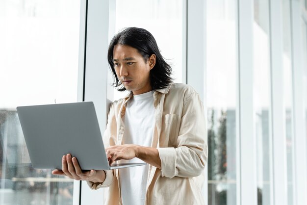 Hombre asiático usando laptop mientras está en la ciudad