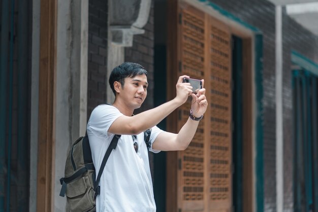 Hombre asiático viajero que usa un teléfono móvil para tomar una foto mientras pasa un viaje de vacaciones a Pekín, China