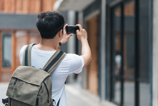 Hombre asiático viajero que usa un teléfono móvil para tomar una foto mientras pasa un viaje de vacaciones a Pekín, China