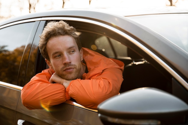 Foto gratuita el hombre asoma la cabeza por la ventana del coche durante un viaje por carretera