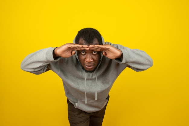 Foto gratuita hombre asomando afroamericano, posando en la pared amarilla y azul.