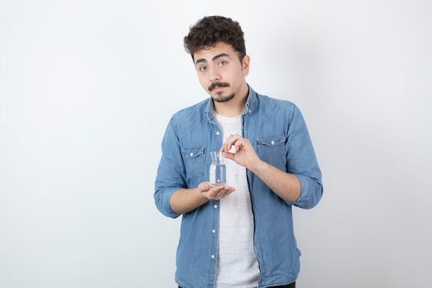 Hombre de aspecto serio sosteniendo un vaso de agua en blanco.