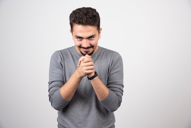 Hombre astuto en camiseta gris contra blanco.