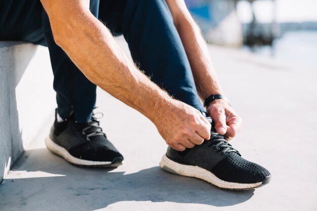 Hombre atando los cordones de sus zapatos izquierdos