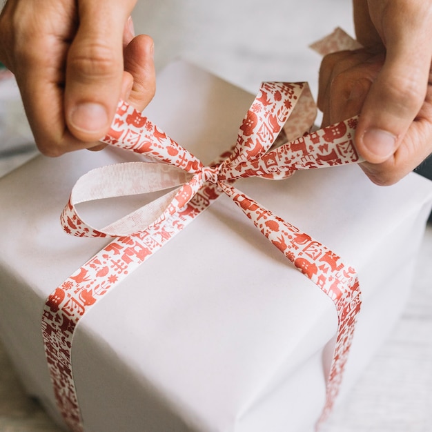 Hombre atar arco en caja de regalo grande