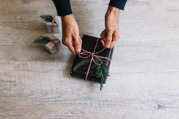 Foto gratuita hombre atar arco en caja de regalo negro