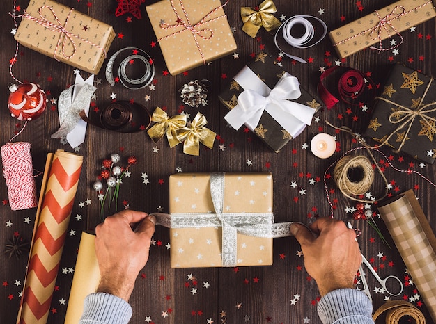 Hombre atar arco en el proceso de caja de regalo de Navidad de paquete caja de regalo de año nuevo