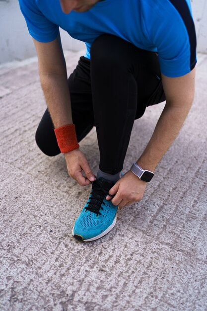 Hombre atar sus zapatos deportivos sobre fondo de hormigón