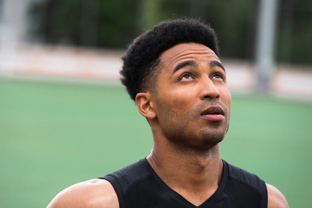 Hombre atleta africano concentrado en la pista de atletismo al aire libre