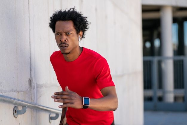 Foto gratuita hombre atlético afro corriendo y haciendo ejercicio al aire libre en la calle