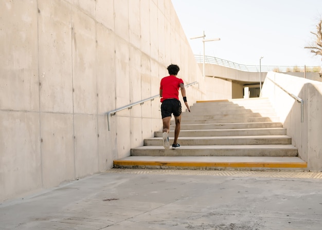 Hombre atlético afro corriendo y haciendo ejercicio al aire libre. Concepto de deporte y estilo de vida saludable.