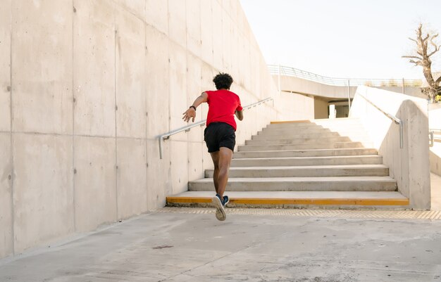 Hombre atlético afro corriendo y haciendo ejercicio al aire libre