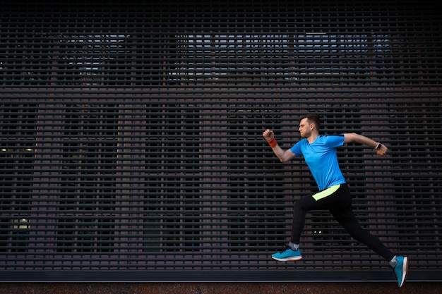 Hombre atlético corriendo en la calle urbana contra el fondo gris