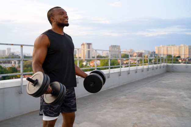 Foto gratuita hombre atlético entrenando al aire libre con pesas