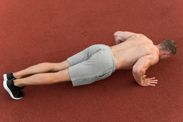 Hombre atlético haciendo flexiones al aire libre