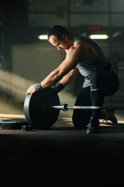 Hombre atlético preparando pesas para entrenamiento con pesas en un gimnasio Copiar espacio