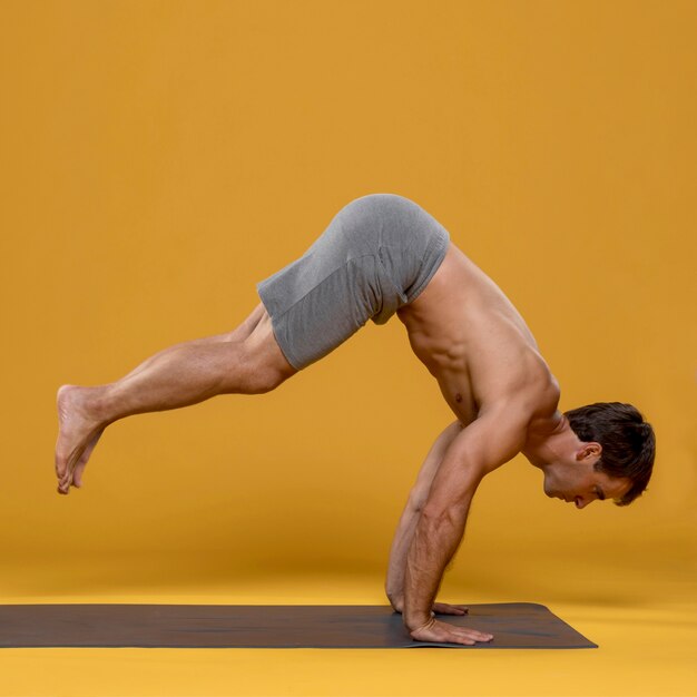 Hombre atlético que ejercita en la estera de yoga