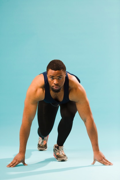 Hombre atlético en traje de gimnasio preparándose para correr