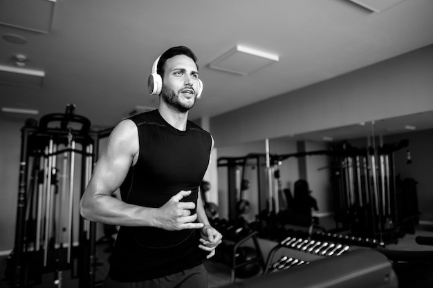 Foto gratuita hombre atlético trotando en la pista de atletismo mientras hace ejercicio en un gimnasio