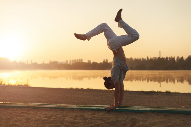 Hombre atlético yoga entrenamiento entrenamiento en el amanecer de playa