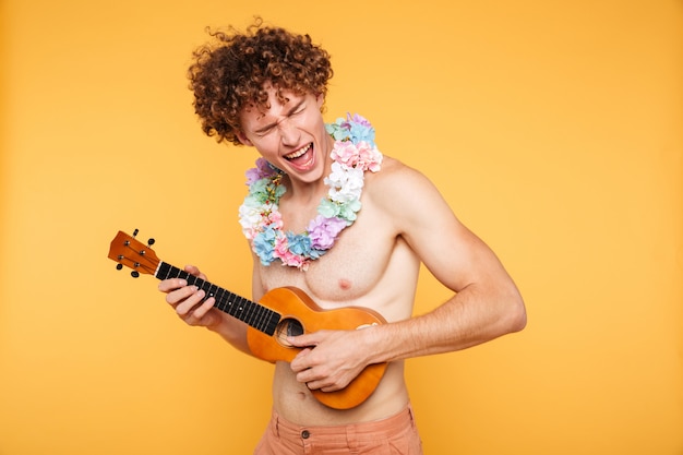 Hombre atractivo sin camisa en ropa de verano tocando el ukelele