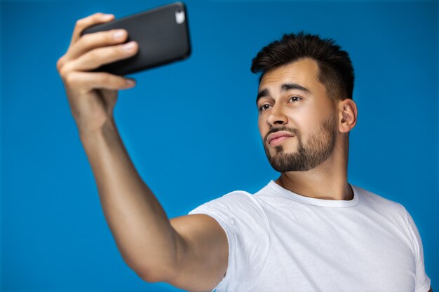 Hombre atractivo está haciendo selfie en su teléfono móvil