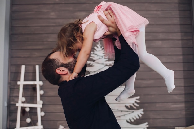 Foto gratuita hombre atractivo feliz sostiene en sus brazos y se divierte con la niña linda en la atmósfera de año nuevo