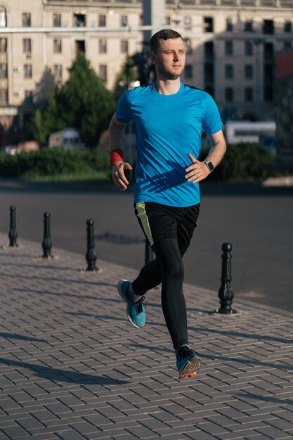 Hombre atractivo en forma corriendo en la ciudad