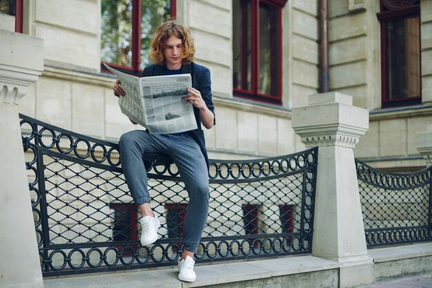 Hombre atractivo leyendo periódico cerca del edificio de estilo antiguo