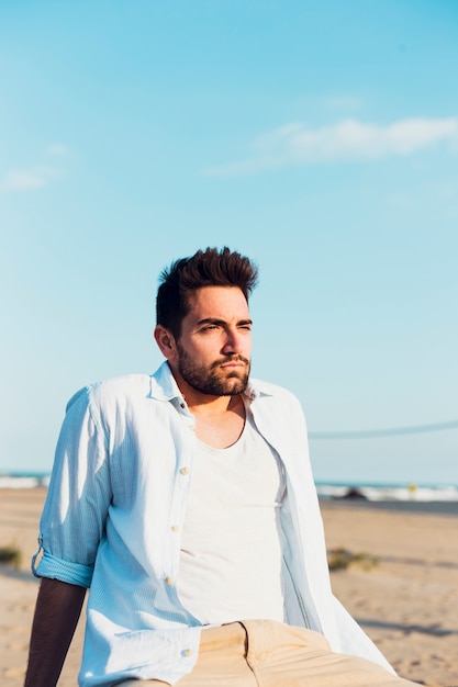 Hombre atractivo en la playa mirando a otro lado