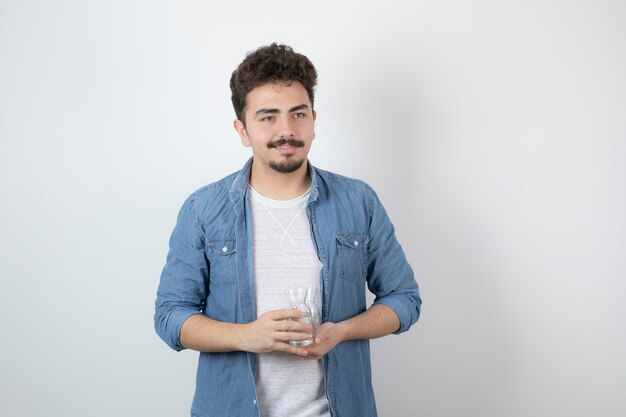 un hombre atractivo sonriente de pie y sosteniendo un frasco de vidrio.