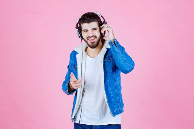 Hombre con auriculares apuntando a alguien de la derecha