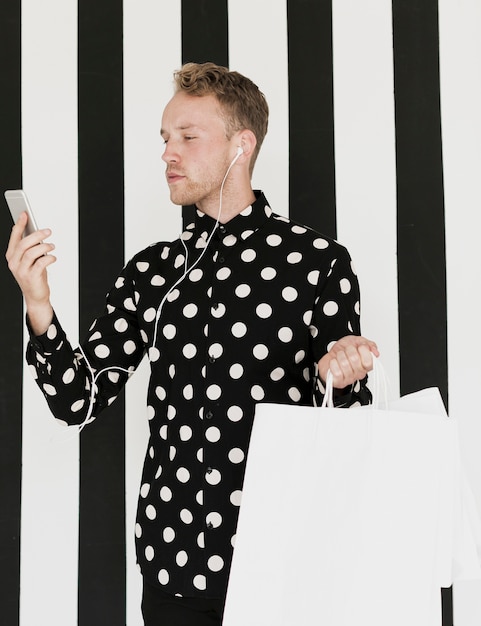 Hombre con auriculares y bolsas de compras