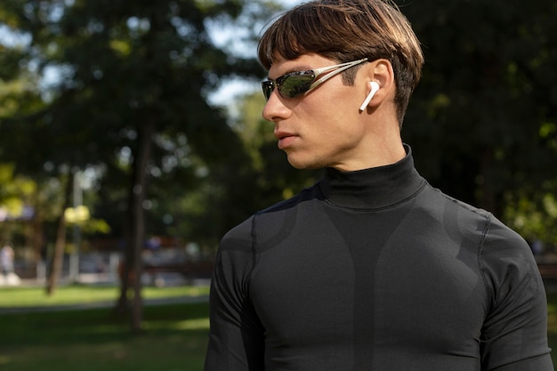 Hombre con auriculares y gafas de sol trabajando al aire libre