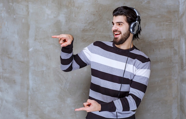 Foto gratuita hombre con auriculares mostrando el tamaño de un objeto