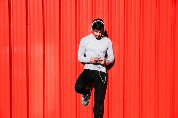 Hombre en auriculares, navegación por teléfono inteligente mediante el entrenamiento