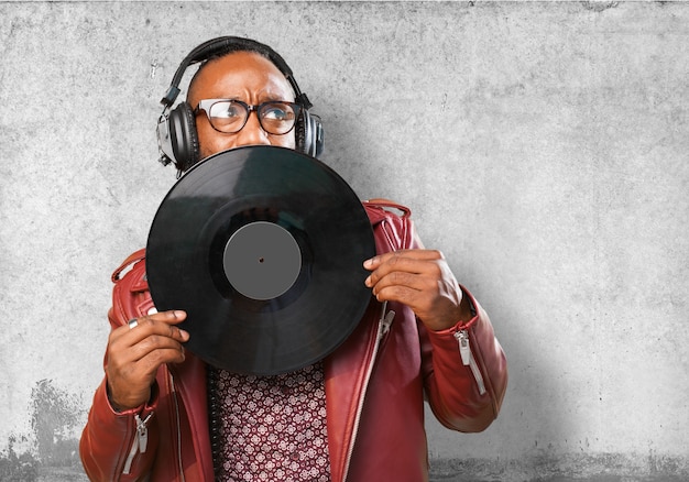 Hombre con auriculares tapándose la boca con un disco de vinilo