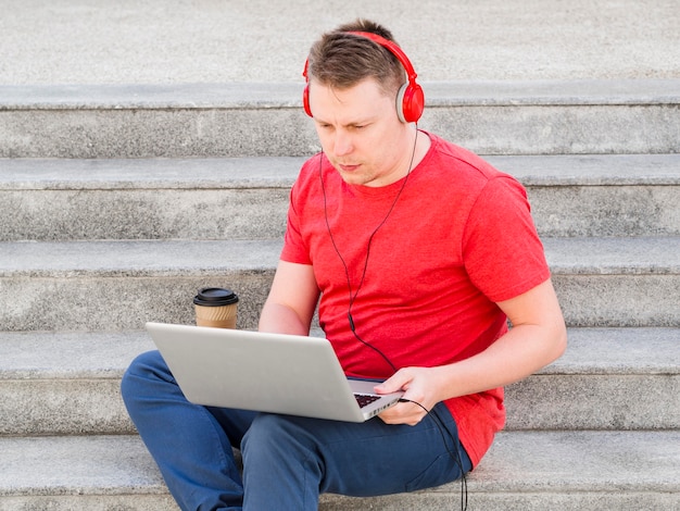 Hombre con auriculares trabajando en pasos con laptop