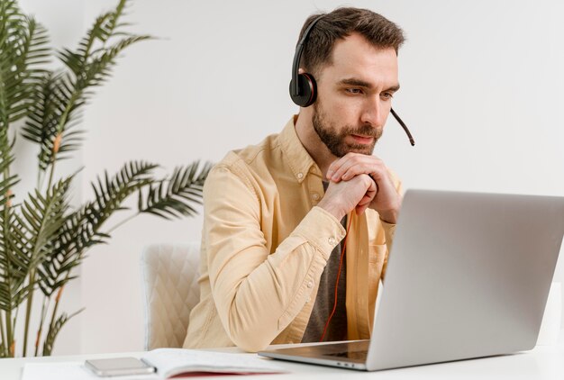 Hombre con auriculares con videollamada en portátil