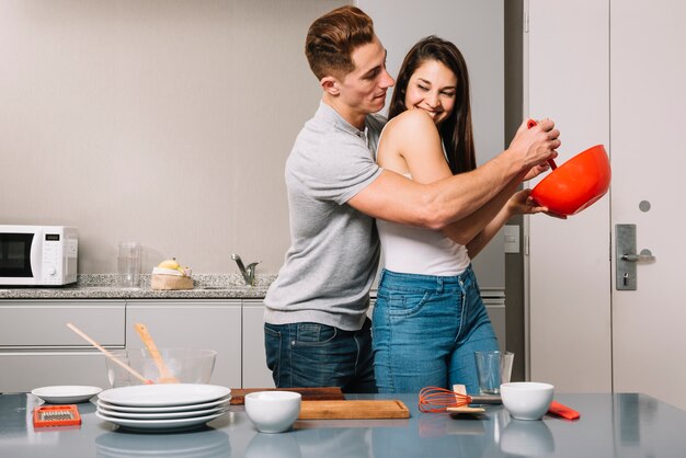 Hombre ayudando a una mujer mezclando comida en un tazón