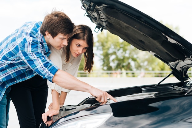 Hombre ayudando a mujer reparar coche