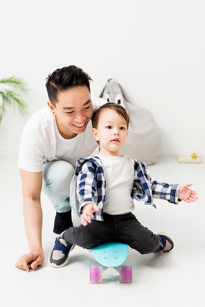 Foto gratuita hombre ayudando a niño usando patineta en casa