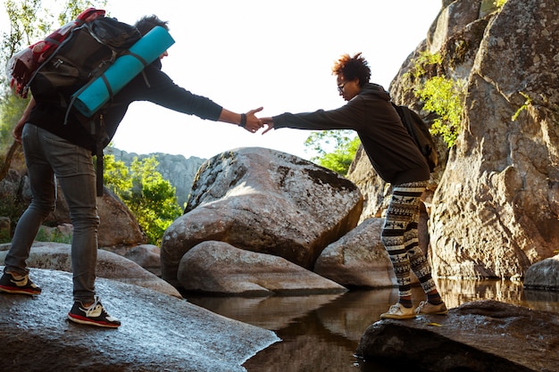 Hombre ayudando a su novia a sobrepasar el agua en el cañón