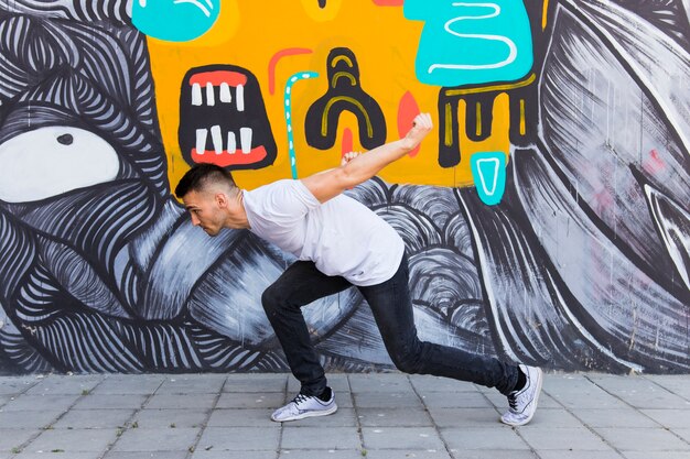 Hombre bailando frente a la pared pintada