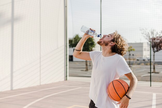 hombre con baloncesto bebiendo agua