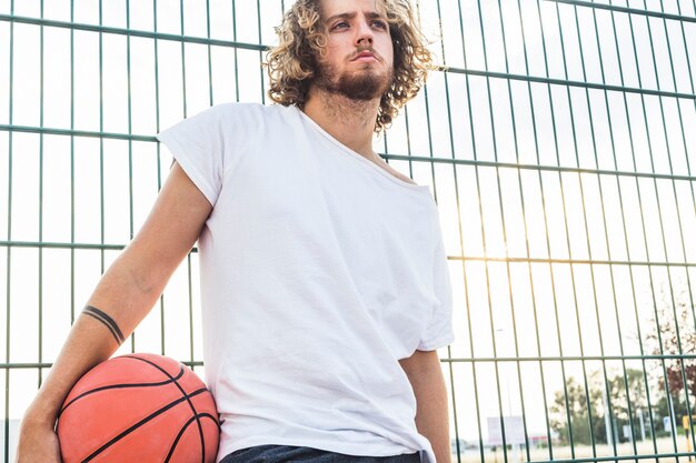 Hombre con el baloncesto de pie delante de la cerca