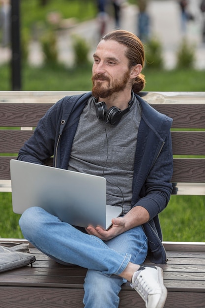 Hombre en banco al aire libre con laptop