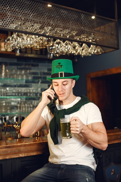 Hombre en el bar con cerveza. guy celebra el día de san patricio. hombre con sombrero verde.