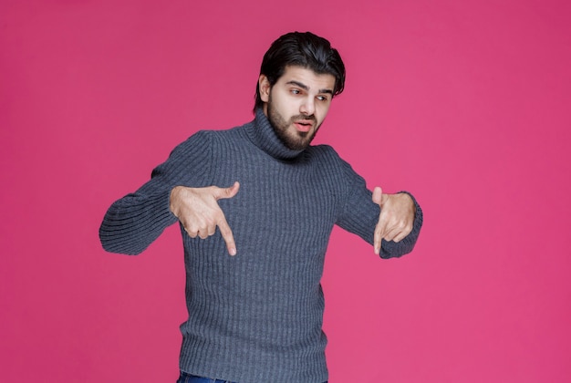 Hombre con barba apuntando a algo debajo.