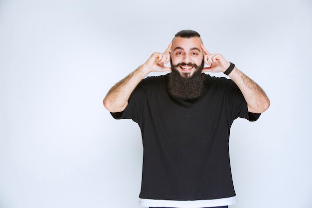 Foto gratuita hombre con barba asomando la cabeza, sonriendo y pensando.